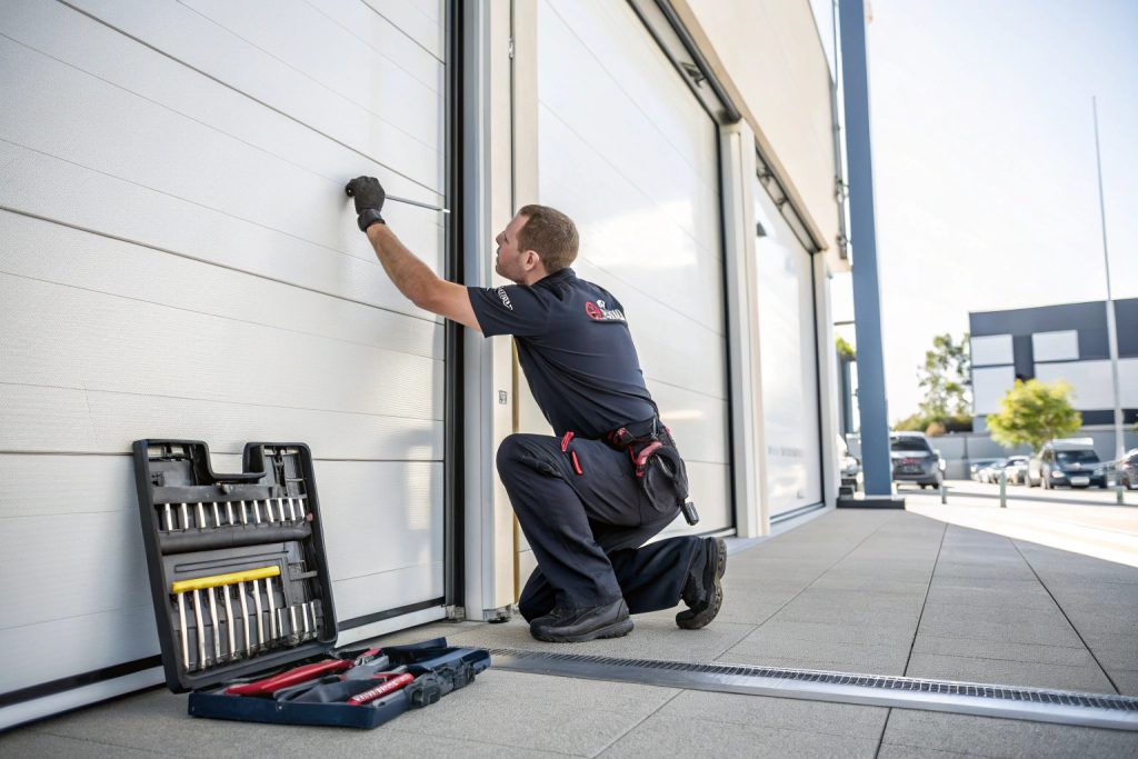 Commercial door service technician performing professional maintenance on roller door in Bankstown